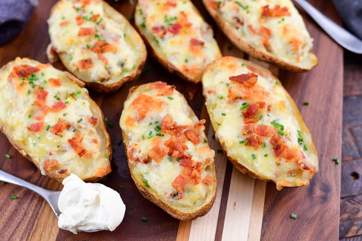 Twice smoked baked potatoes on a wood board with sour cream