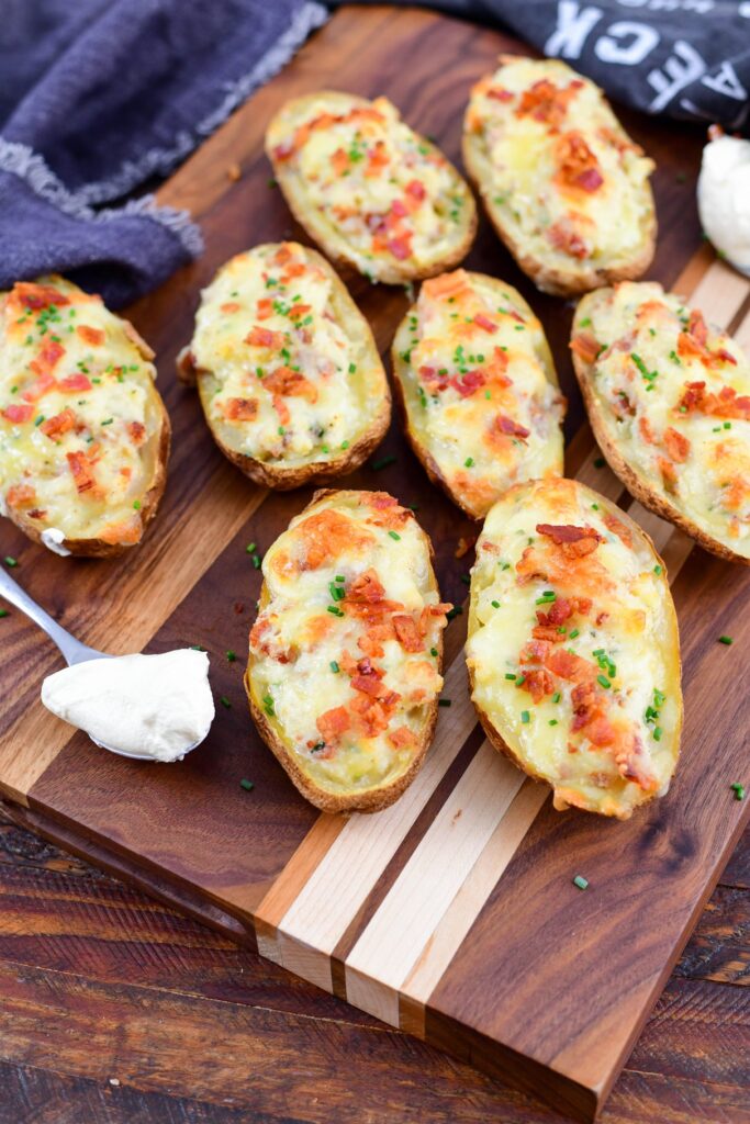 Twice smoked baked potatoes on a wood board with sour cream