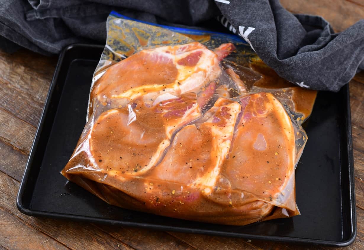 raw pork chops on a cooking tray marinating in a bag