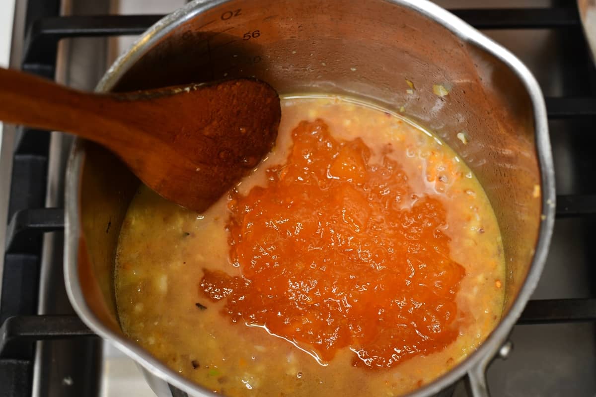 Peach preserves added to cooking sauce in a medium sauce pan.