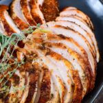 thinly sliced turkey breasts stacked on the black platter.