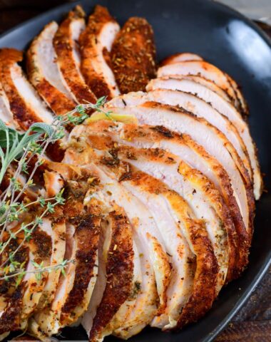 thinly sliced turkey breasts stacked on the black platter.