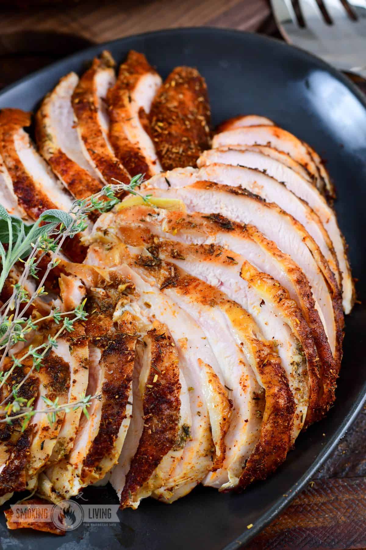 thinly sliced turkey breasts stacked on the black platter.