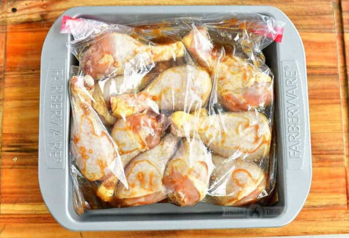 Chicken legs in a bag with marinade in a baking dish.