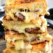 side view of 4 steak grilled cheese halves stacked on to of each other